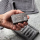 A man holds a lathered bar of pine tar scrub soap.