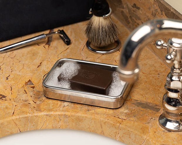 Sudsy pine tar bar soap sitting on a bathroom countertop. 